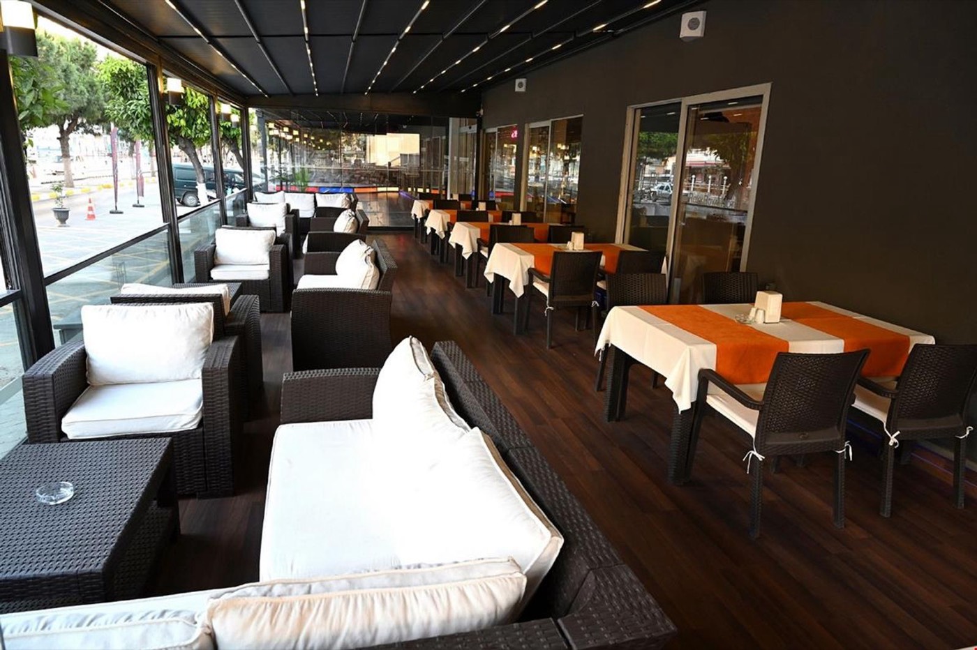 Bulvara bakan, beyaz minderli koltukları ve masalarıyla kapalı teras restoran